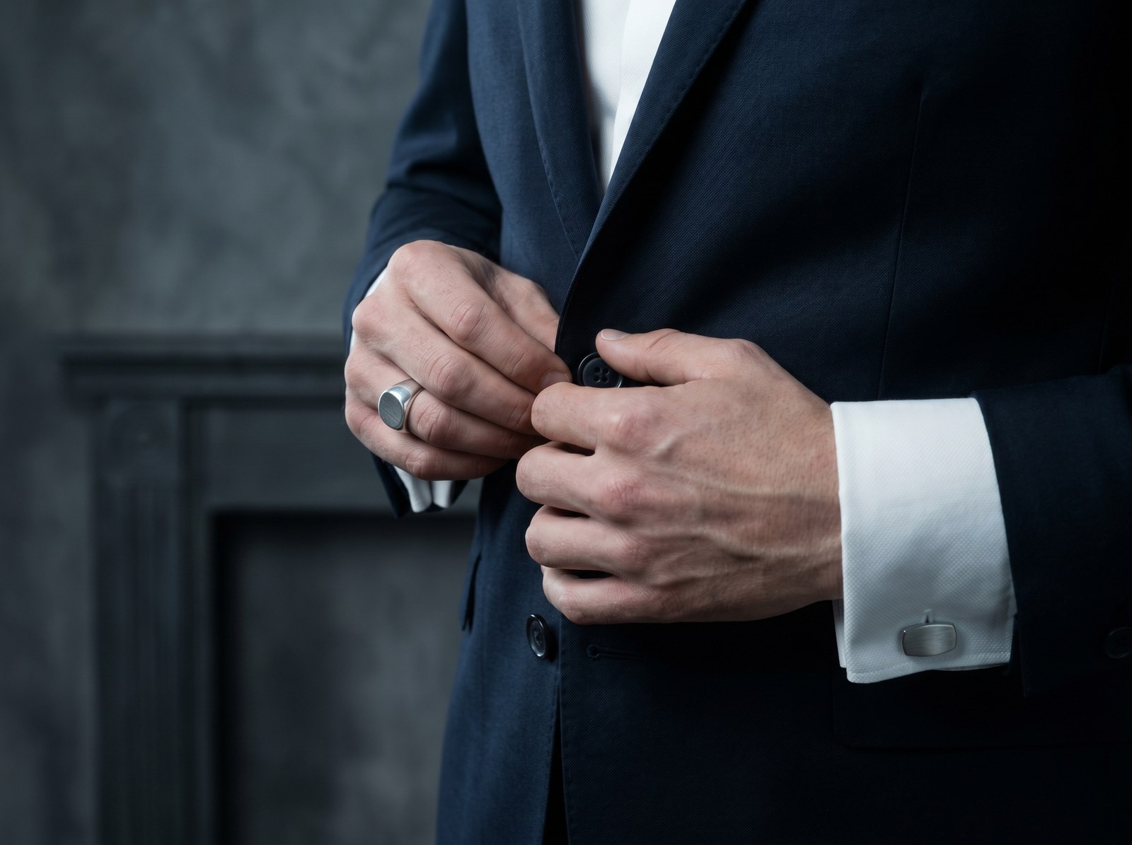 Hands fastening an immaculate navy suit jacket